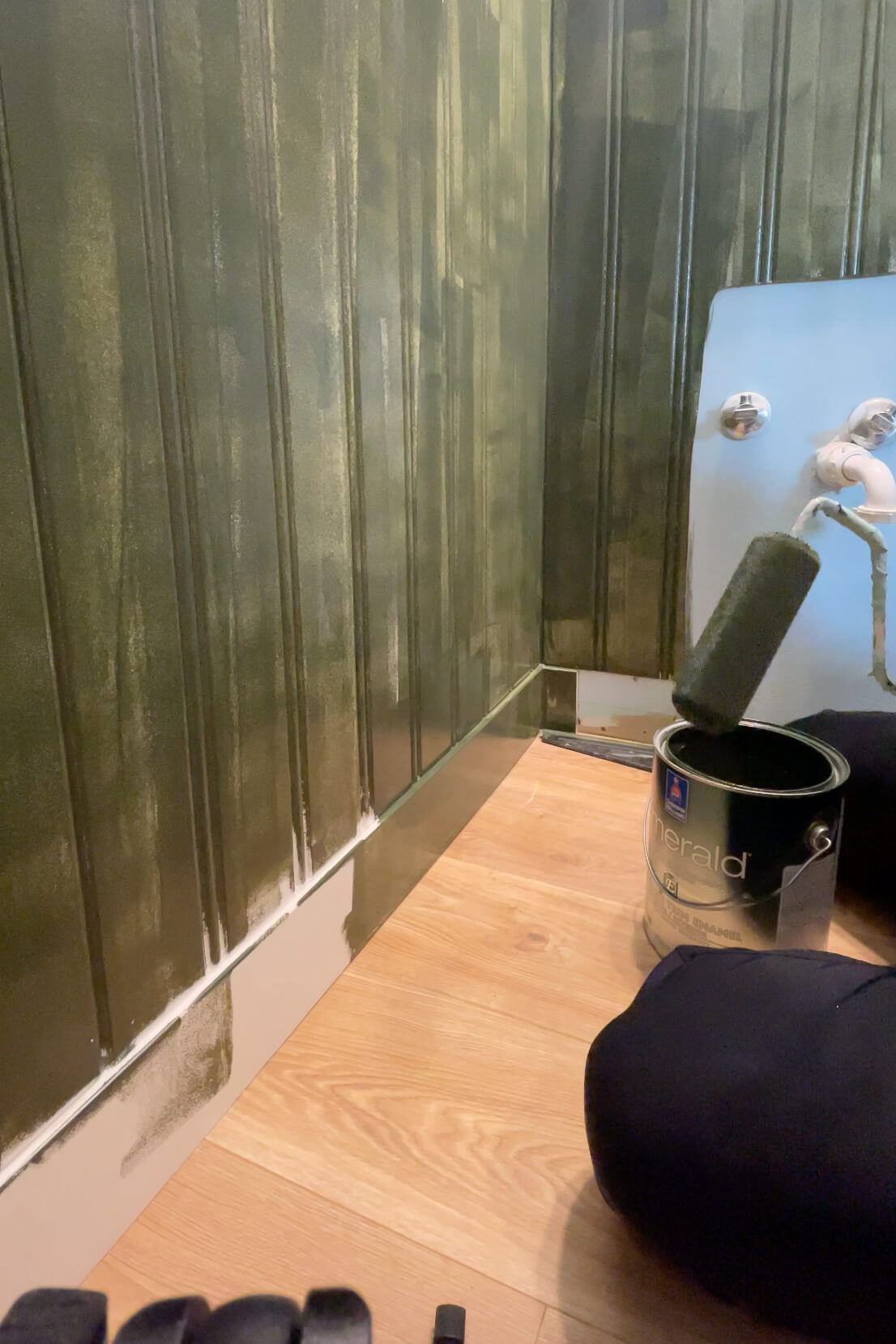 Using a foam roller to paint a beadboard bathroom wall.